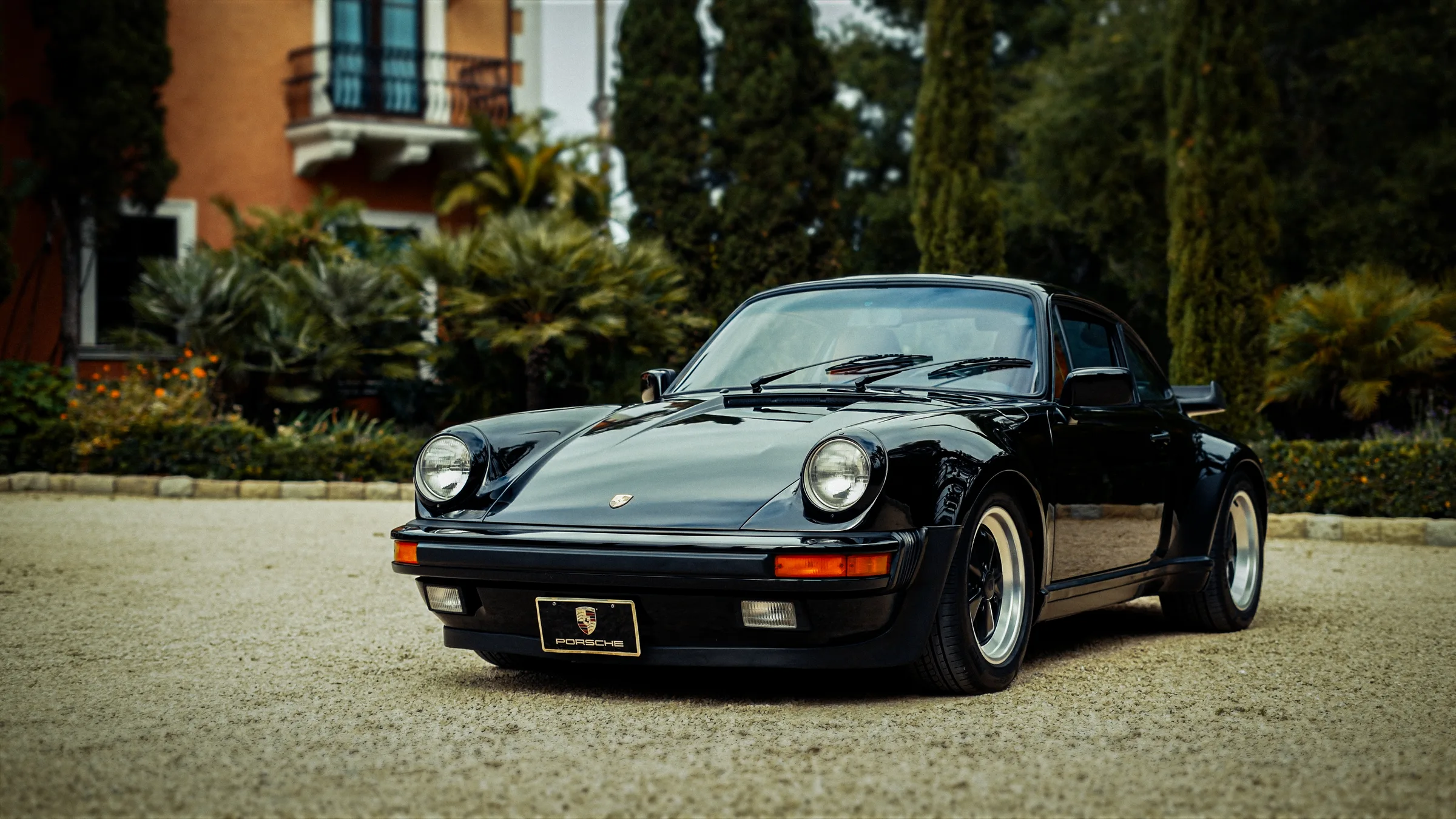 Black Porsche 911 parked in a villa driveway